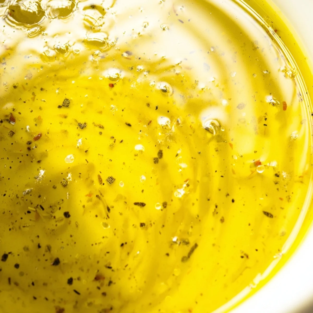 Whisked easy lemon vinaigrette dressing shown with olive oil, fresh lemons, and dijon mustard ingredients