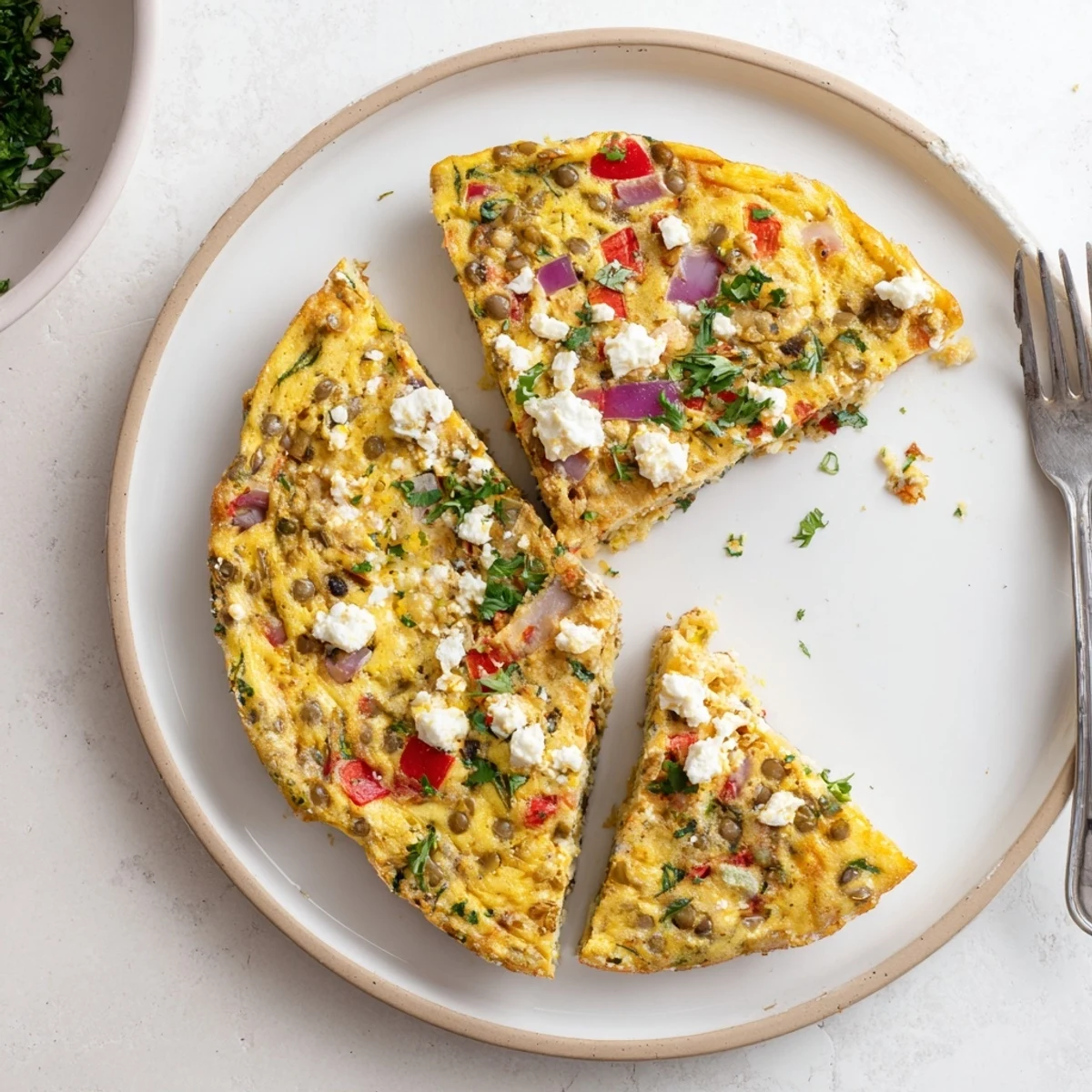 Protein-packed Mediterranean frittata featuring tender lentils, colorful vegetables, and creamy melted feta cheese topping