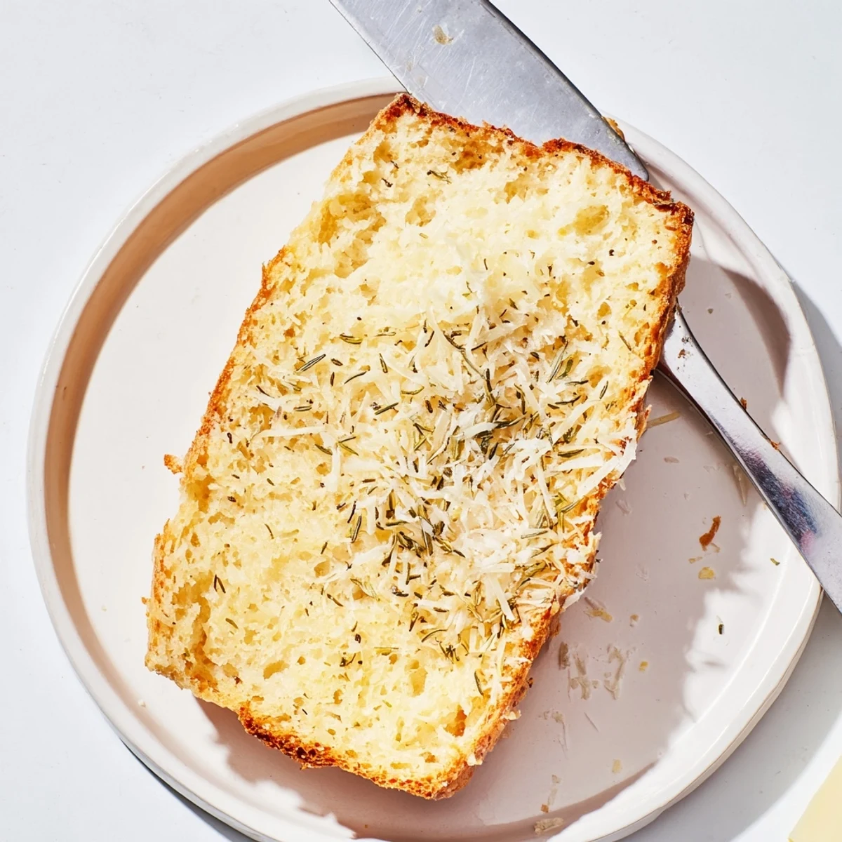 Savory low-carb Parmesan herb keto bread sliced and served on wooden cutting board with butter