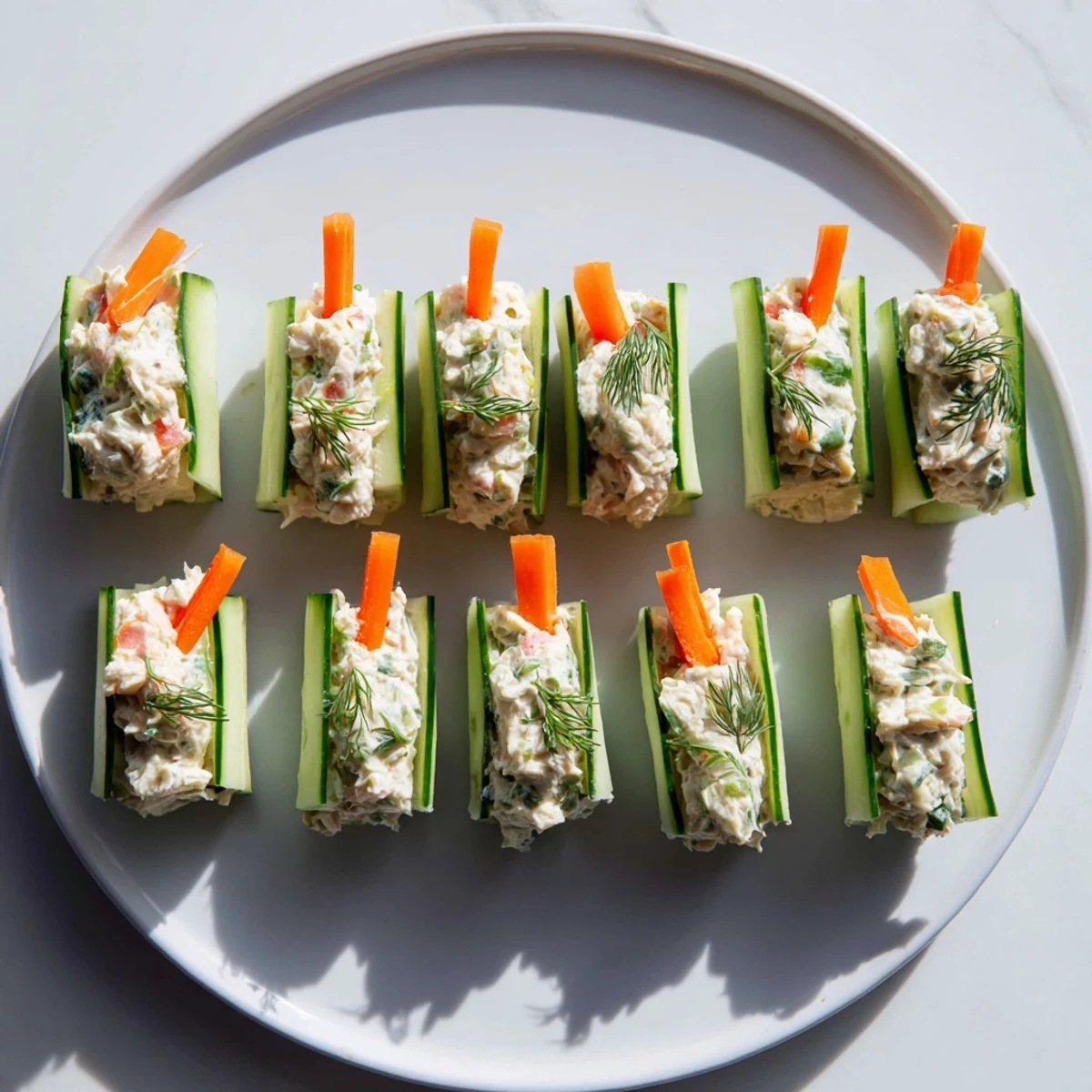 Handheld cucumber roll ups filled with savory chicken salad and colorful julienned carrot strips