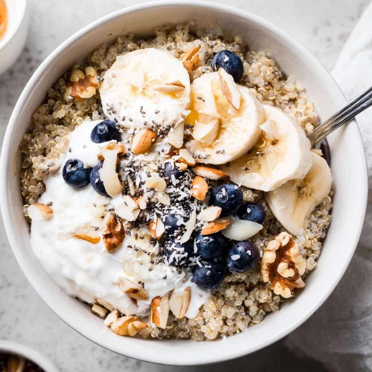 Vibrant blueberry quinoa breakfast bowl arranged with yogurt, nuts, and shredded coconut toppings