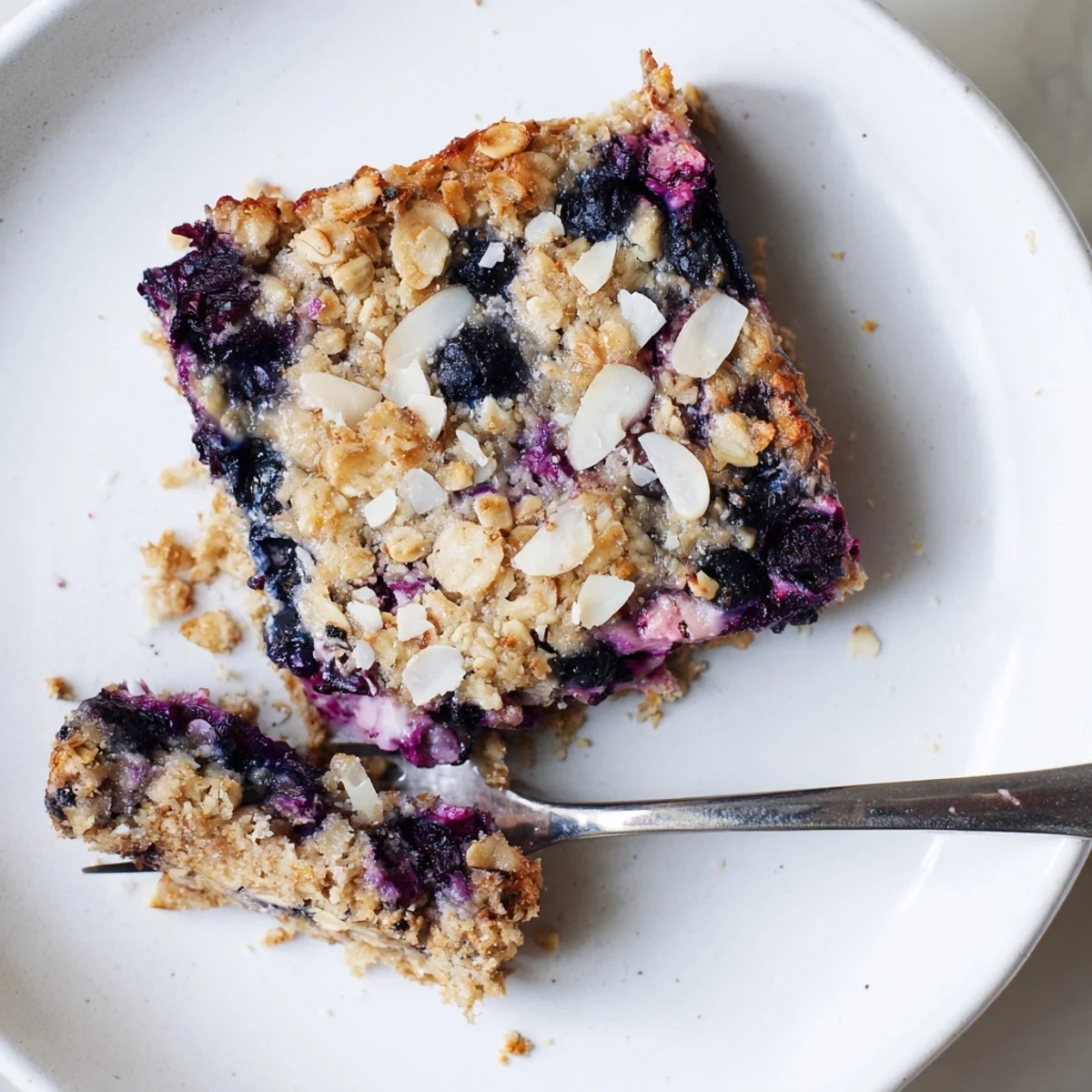 Sliced blueberry cottage cheese breakfast bake serving with plump berries and creamy oat texture on a white plate