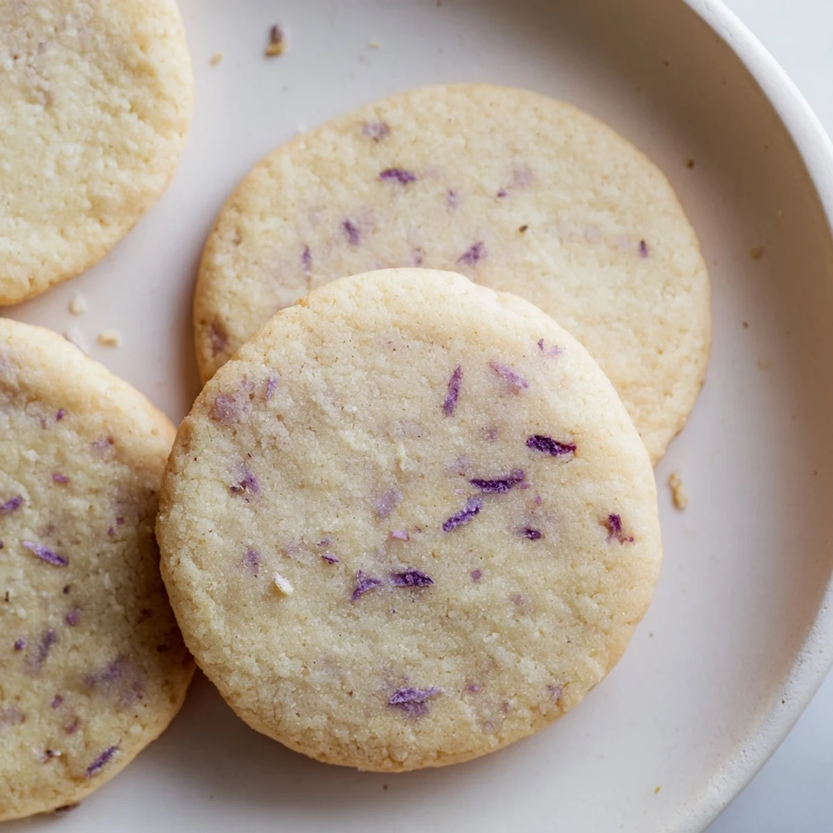 Soft lilac sugar cookies with pale purple edges arranged on a rustic wooden serving board