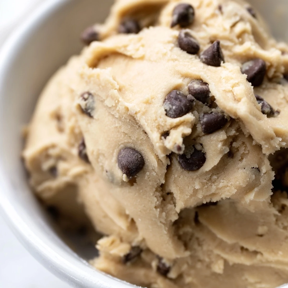 Creamy chocolate chip cookie dough scooped into balls with semisweet chips throughout