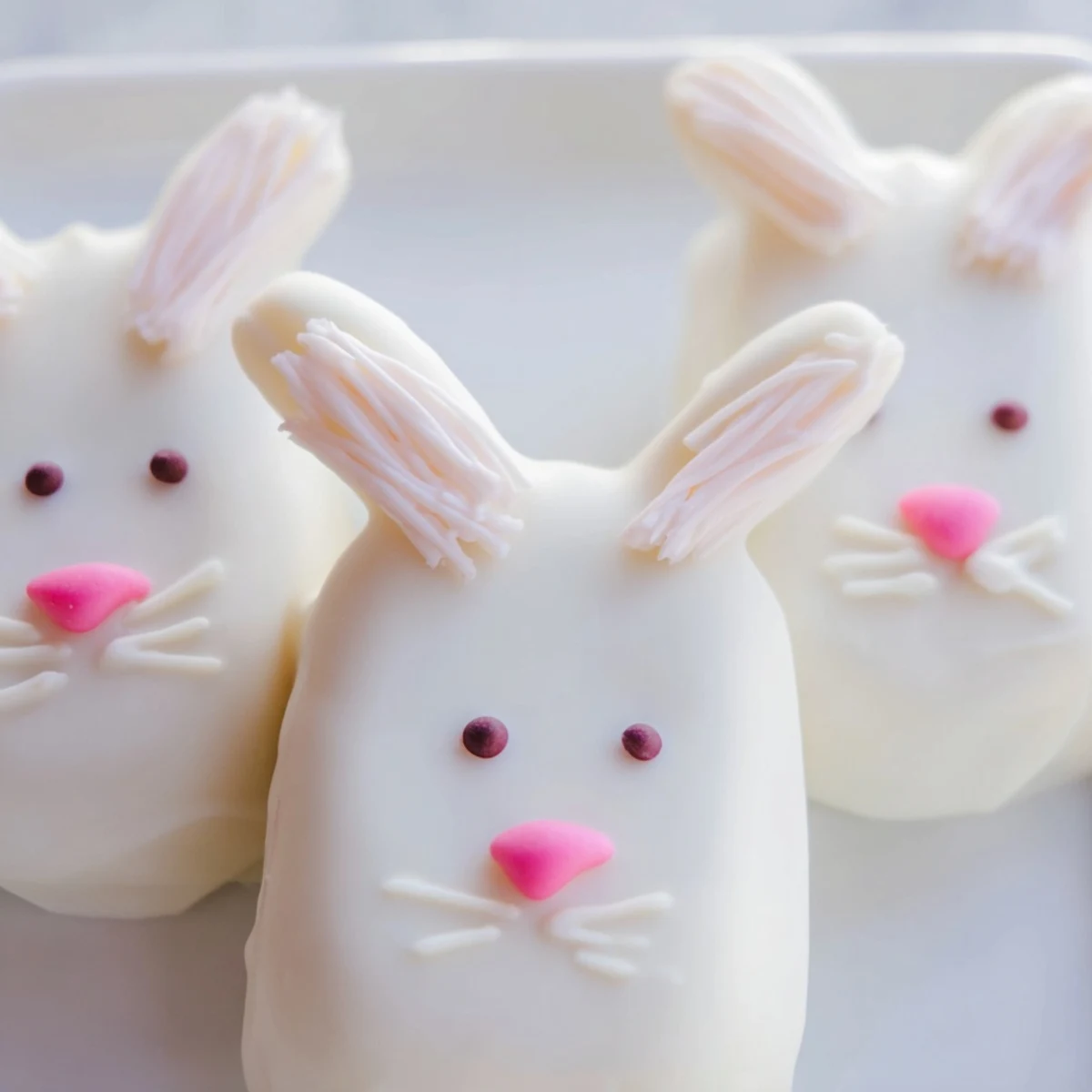 Adorable white chocolate bunny cakesicles with candy eyes and pink ears on sticks