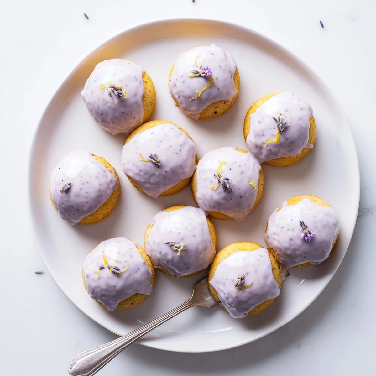 Golden mini lemon cakes with lavender glaze dripping over tender crumb tops