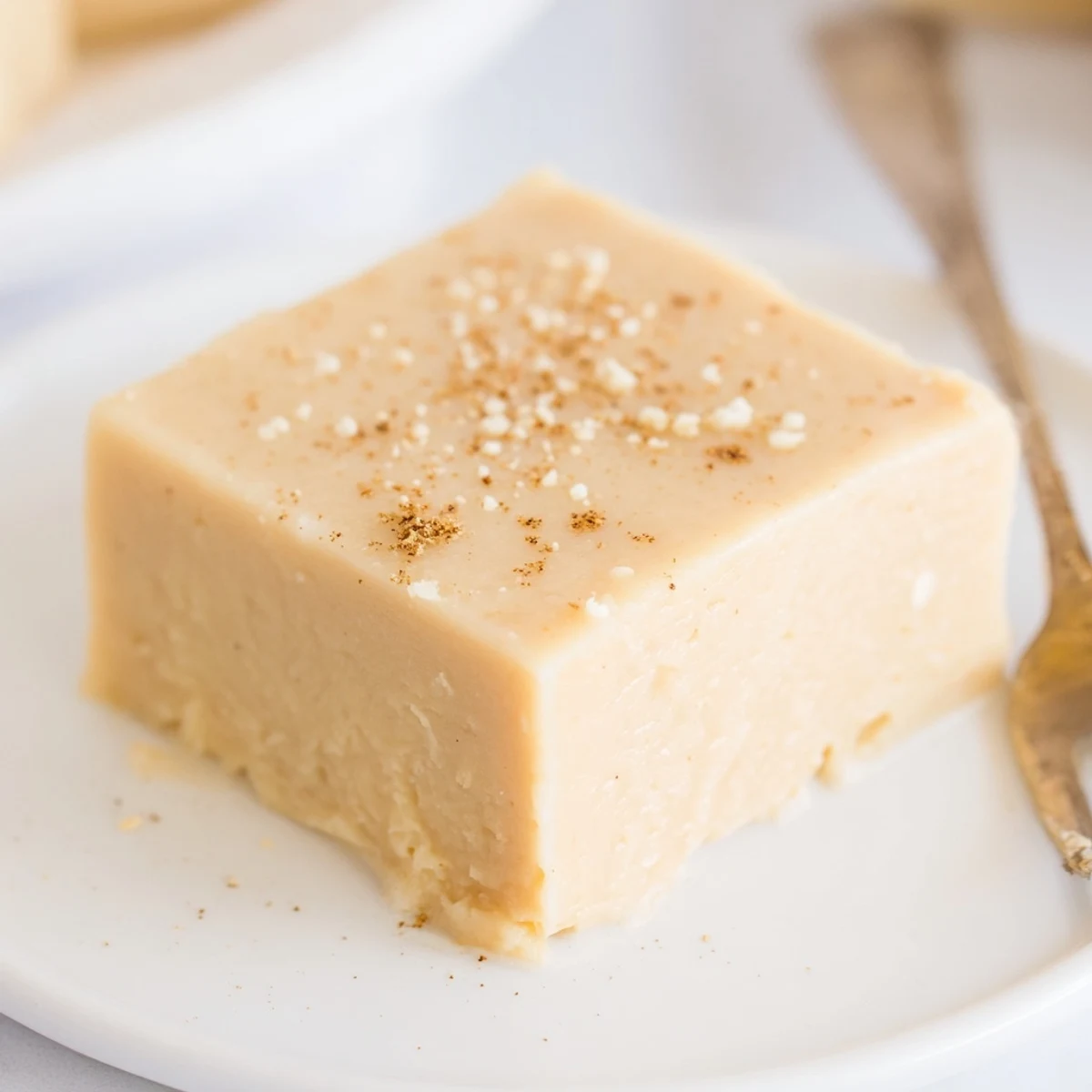 Creamy Eggnog Fudge squares dusted with nutmeg on parchment, holiday-ready.