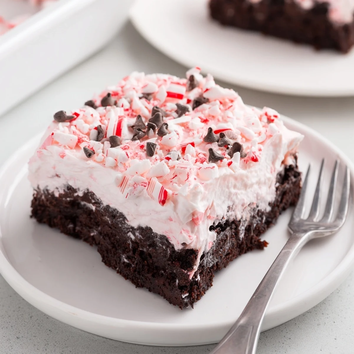 Holiday Peppermint Poke Cake garnished with chocolate shavings, served on plate.