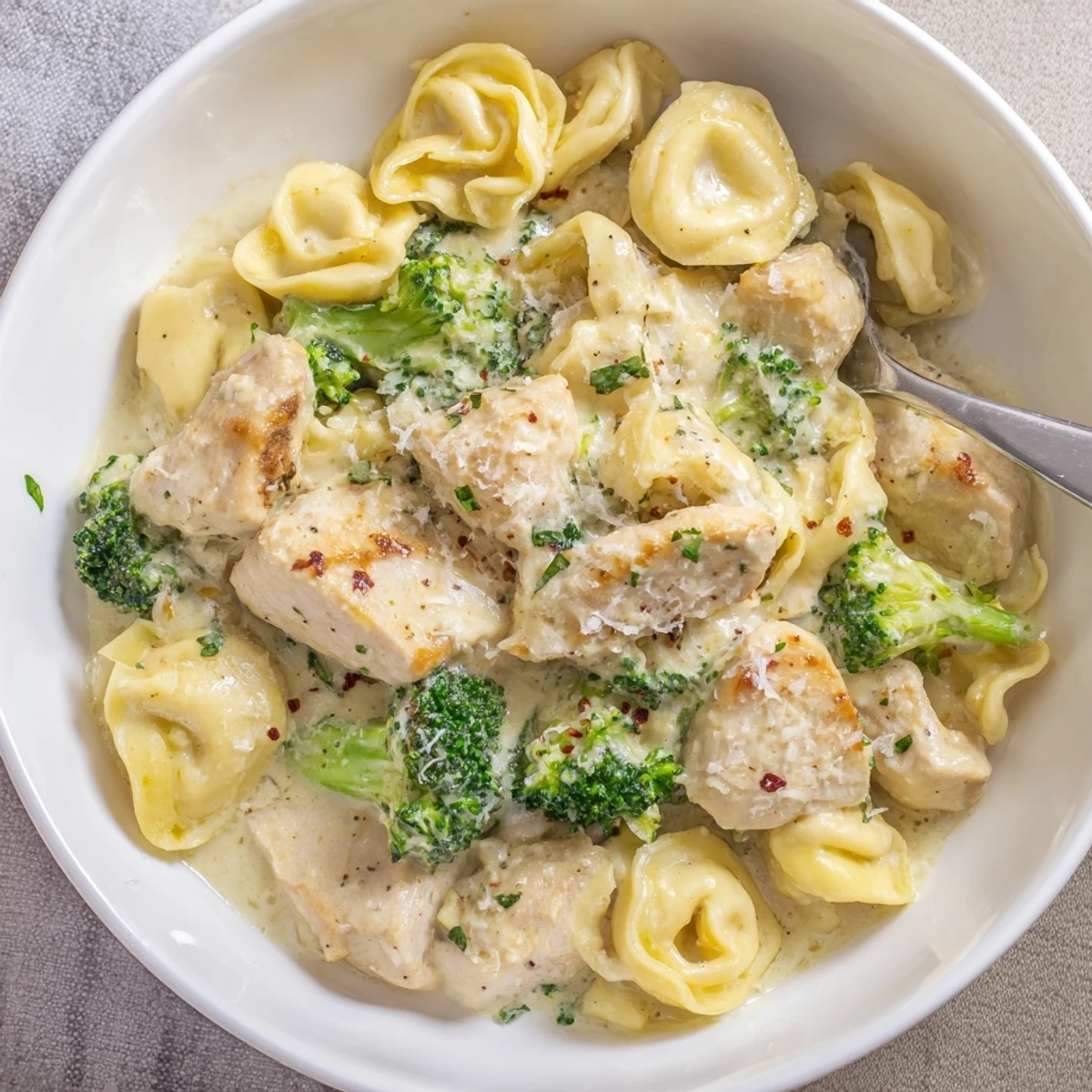 Skillet of Creamy Garlic Parmesan Tortellini Chicken Broccoli Recipe with golden seared chicken bites