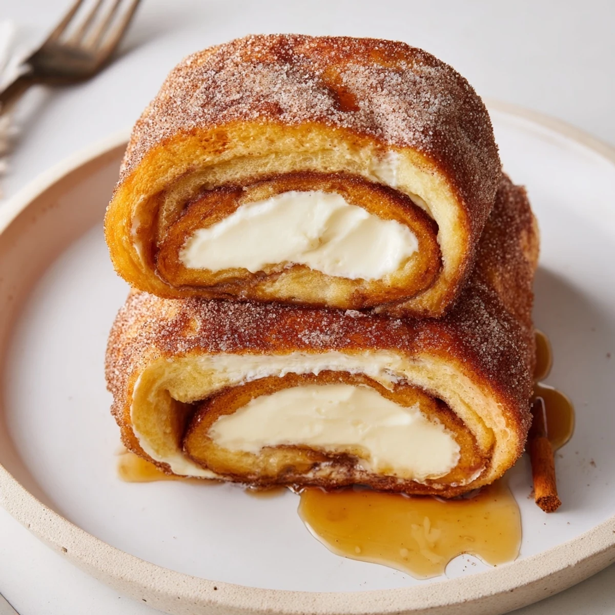 Warm, skillet-browned Cinnamon Roll French Toast Roll Ups with syrup-ready sheen