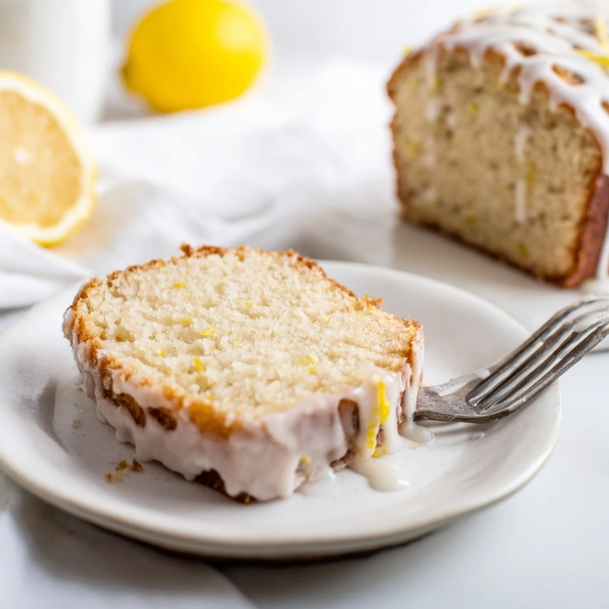 Moist lemon loaf cake with powdered sugar glaze cooling on a wire rack