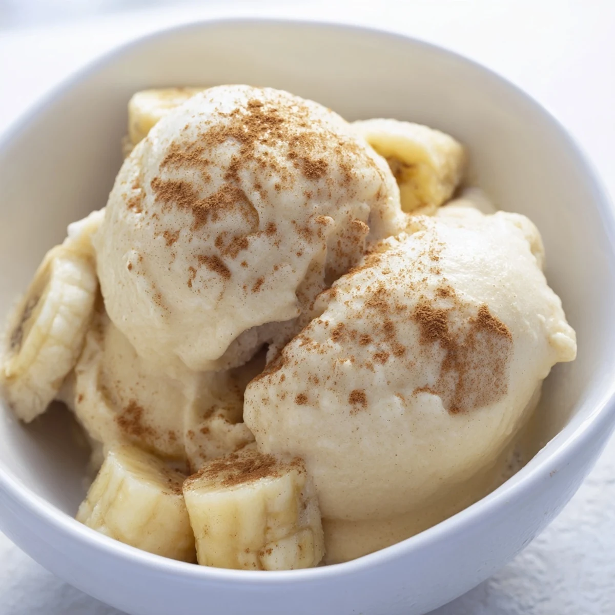 Creamy banana nice cream scooped into a bowl with fresh banana slices on top