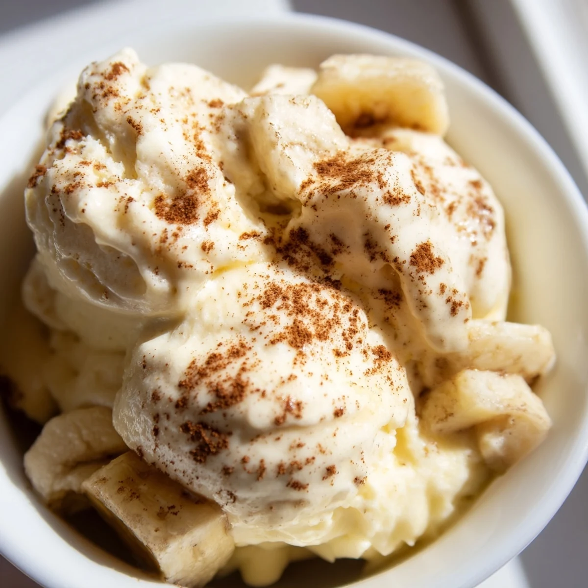 Dairy-free banana nice cream swirling in a glass bowl with smooth soft-serve texture