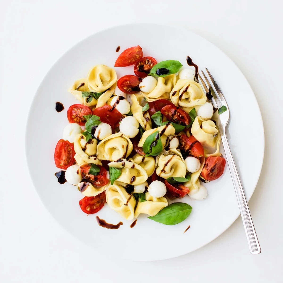 Garden-fresh tortellini caprese salad featuring al dente cheese pasta, juicy tomatoes, and creamy mozzarella