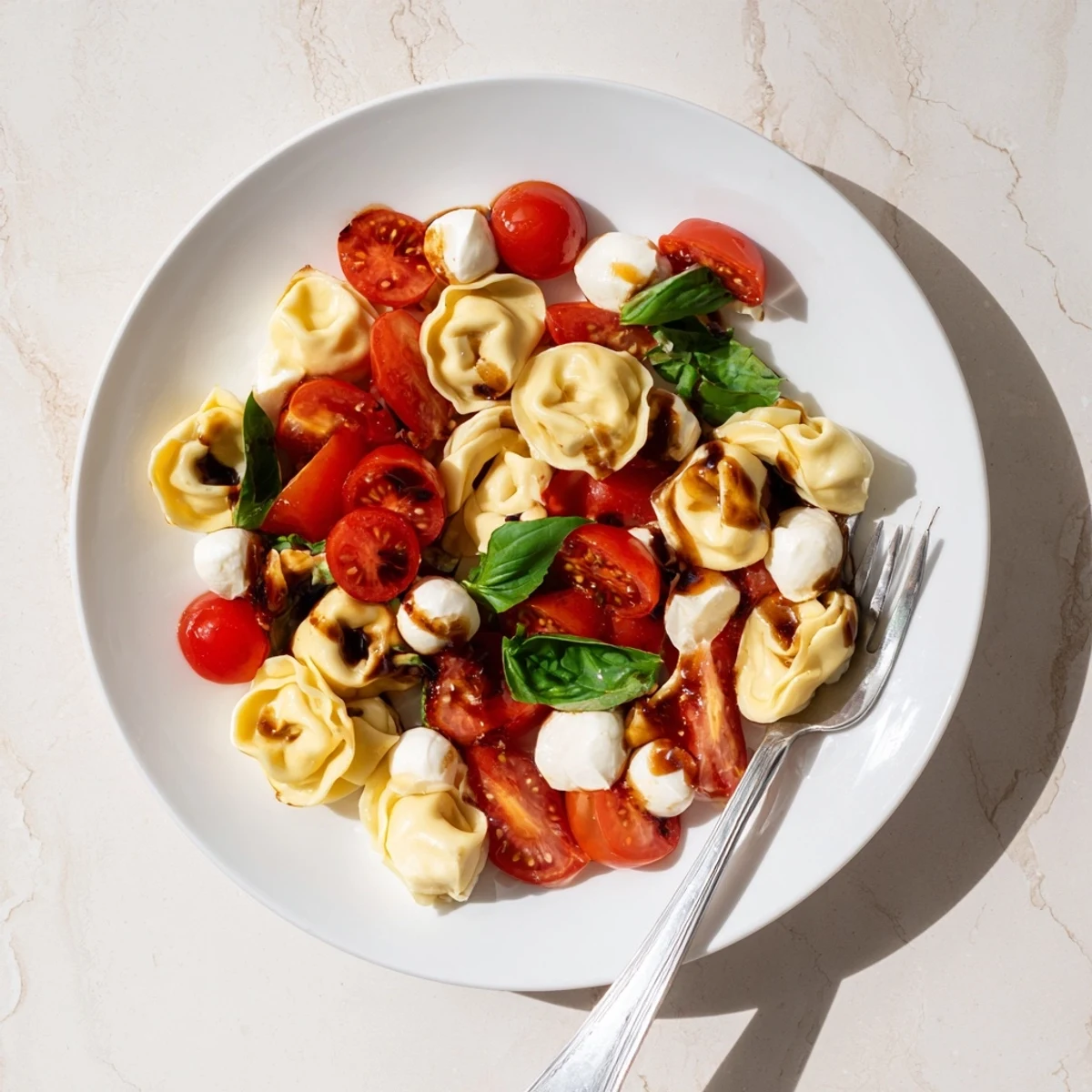 Summer tortellini caprese salad with tender cheese-filled pasta, fragrant basil, and glazed balsamic dressing
