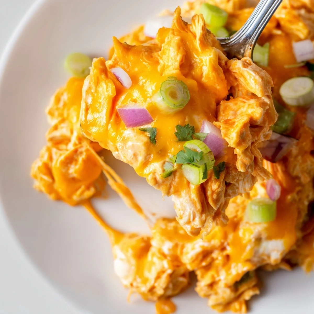 Steaming spoonful of jalapeno buffalo chicken casserole with diced jalapeños and crispy golden cheese