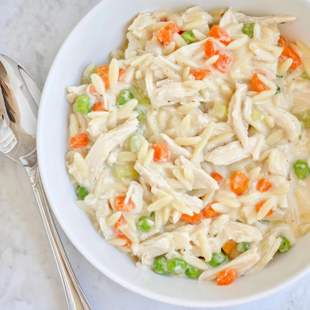 Creamy chicken pot pie orzo with tender chunks, peas, carrots, and parsley in a rich sauce.