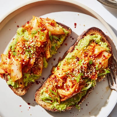 Creamy mashed avocado and spicy ruby kimchi piled on golden toasted bread